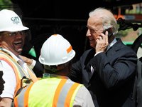 Biden talks on phone while construction workers laugh