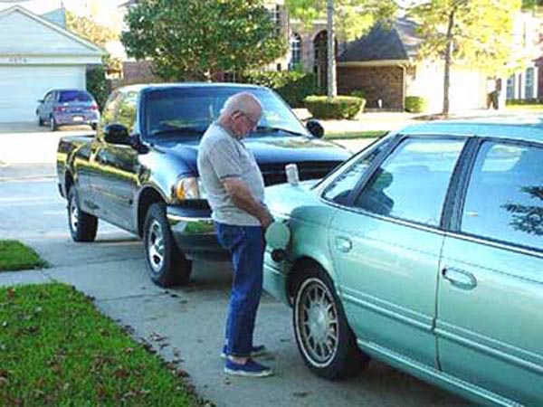 Photos of people doing stupid things - Man peeing in car petrol tank