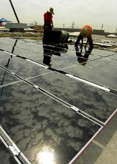 Workers install solar panels on a warehouse rooftop in California. Eventually there will be 33,700 on the structure. Courtesy of Southern California Edison