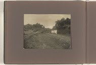 Zeven mannen in lichte pakken op een rij in een landschap