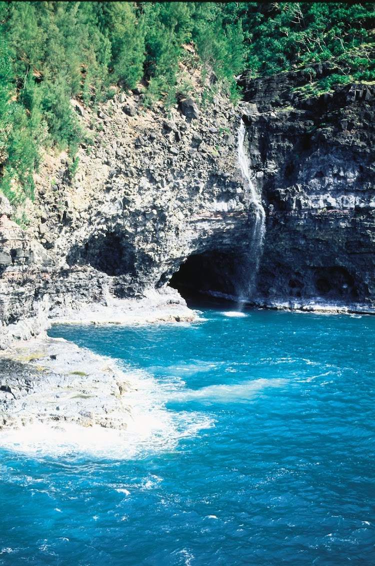 Waterfall and sea caves along Kauai's Na Pali Coast.