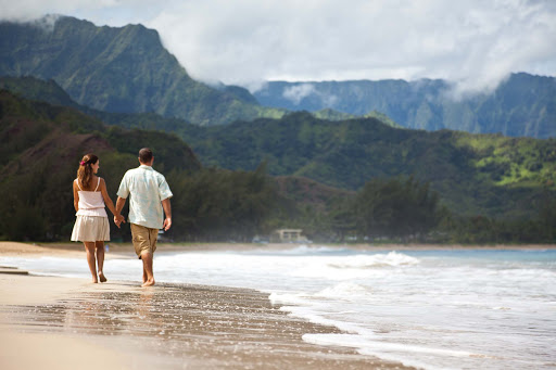 A couple walks along the beach in Kauai. 