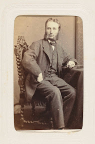 Studioportret van een zittende man met grote bakkebaarden