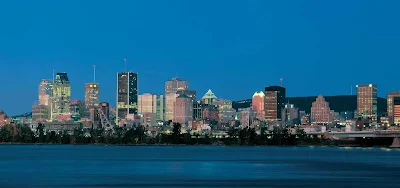 The Montreal skyline over the St. Lawrence River at nightfall.