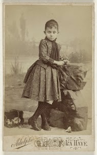 Studioportret van een meisje leunend tegen rotsen met bloemen in haar hand