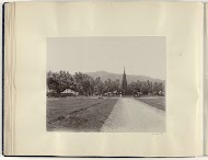 Monument op een plein in Nederlands-Indië met daarvoor een rijtuig en een vélocipède