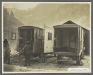 Militairen sjouwen brancards aan de achterzijde van twee ambulances, vermoedelijk Italianen