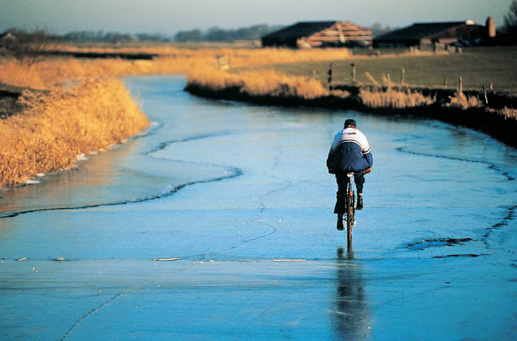 A cyclist on a frozen canal in the Netherlands.
