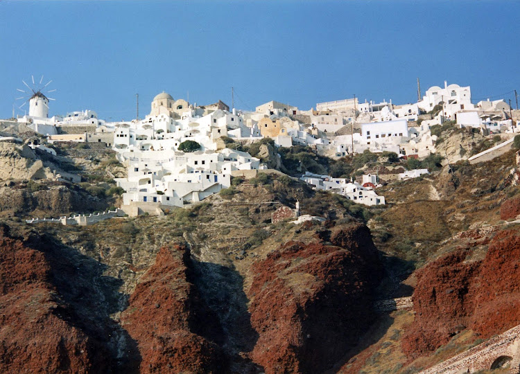 The sugar cube houses of Oia perch atop red rock cliffs that loom over the Aegean Sea on the magical island of Santorini. 