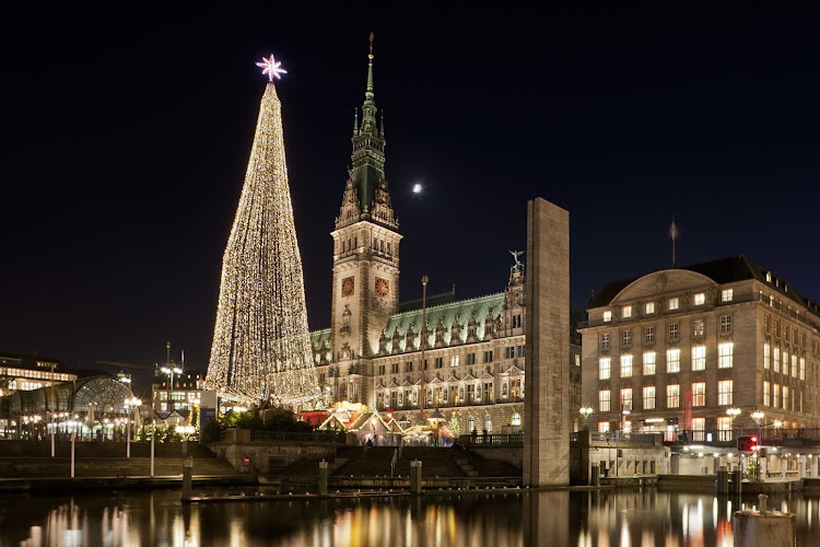 Christmas illuminations light up the evening sky outside the town hall of Alster on the Elbe River in Northern Germany. 