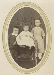 Portret van drie kinderen waaronder een meisje met een jurk en een peuter