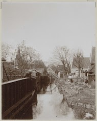 Huizen met erven aan een water, op de achtergrond een kerk, mogelijk in Amsterdam