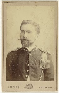 Studioportret van een man met bril, baard en snor gekleed in een leger uniform