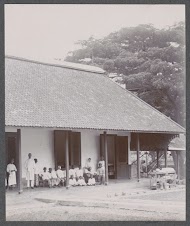 Groep mensen onder een afdak, vermoedelijk patiënten en personeel van een ziekenhuis in Nederlands-Indië