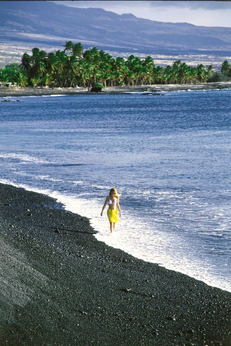 Woman walking on Black Sand Beach, West Kohala Coast, on the Big Island of Hawaii.