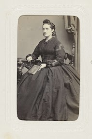 Studioportret van een vrouw op een stoel in een lange zwarte jurk