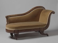 Bank met geel textiel bekleed en rustend op twee conische en op twee hoornvormige poten op klauw, waaronder wielen.