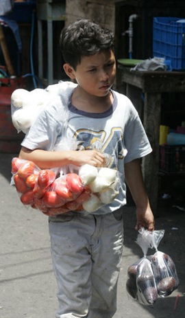 Un menor camina por el centro de  San Salvador para vender tomates, cebollas y aguacates para obtener un ingreso económico y ayudar en su casa. Foto de La Prensa, Tulio Galdámez