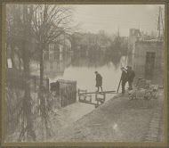 Jongens bouwen een bruggetje in ondergelopen land in een buitenwijk van Parijs