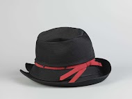 Hoed van zwart doorgestikt satijn versierd met een rood ripslint en zwarte gitten. Samen met hoedendoos van La femme chic Amsterdam.