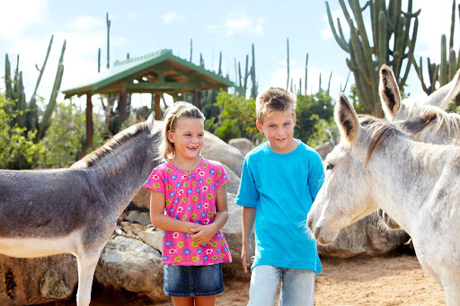 Two young visitors say hello to a donkey at the Aruban Donkey Sanctuary near Santa Cruz, Aruba.