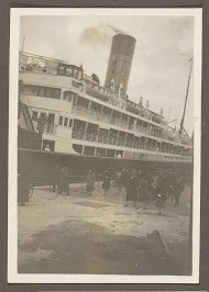 Mensen lopend over een kade naast een aangemeerd schip