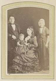 Portret van een man, een baby en twee vrouwen, de één in een jurk, de ander met een muts